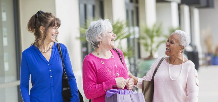 Group of three women laughing outside.