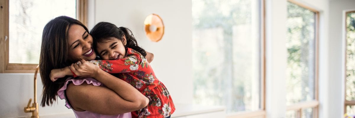 A mother hugs her young daughter.
