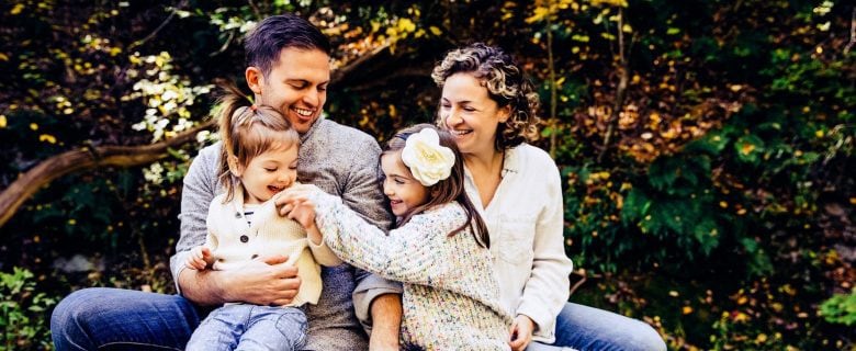A father and mother sit with their two daughters.